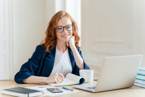 Successful economist in eyewear, checks information on laptop co