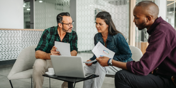 Three people at work looking at their notes and a laptop