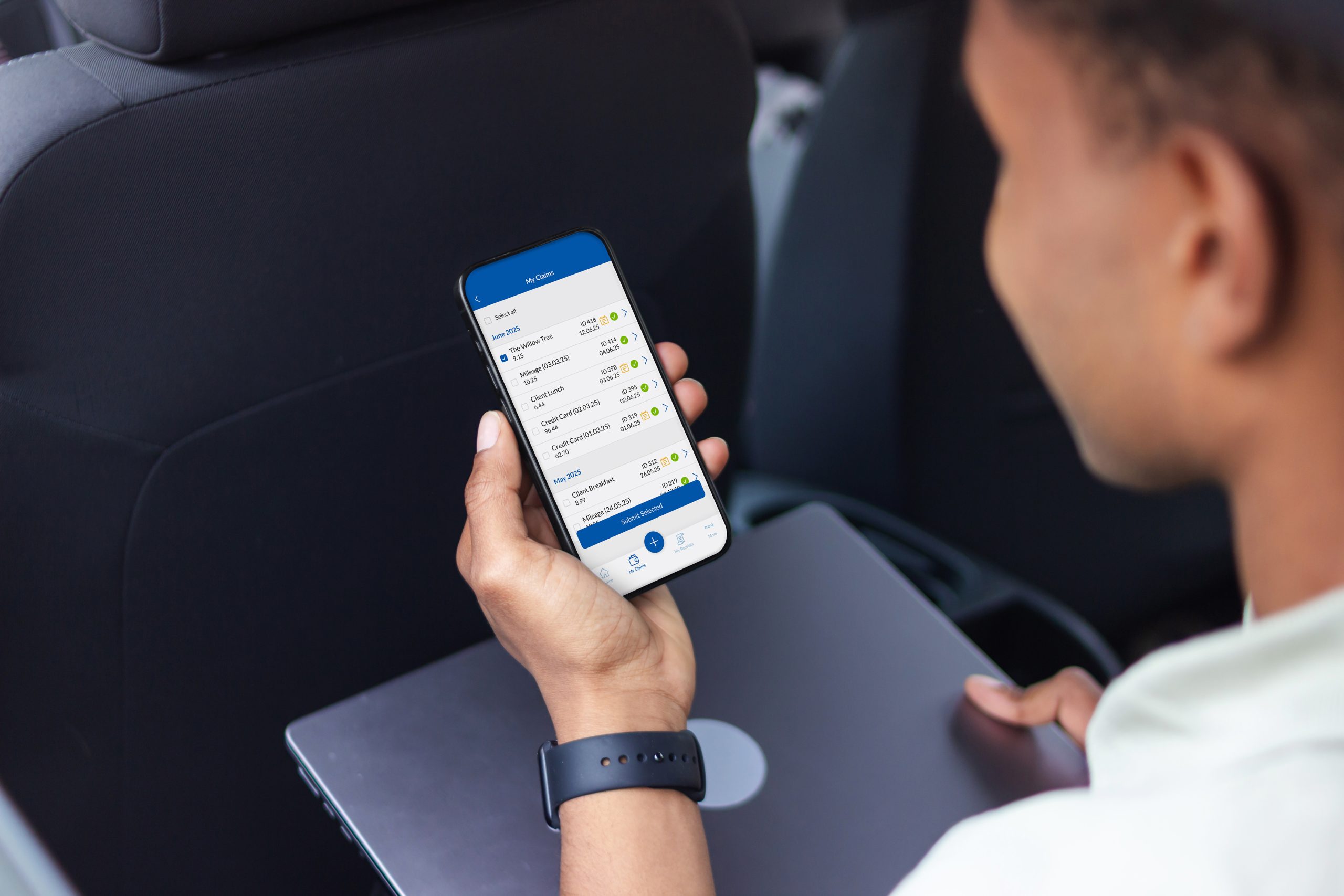 Businessman working with smartphone and laptop while sitting in back seat of car
