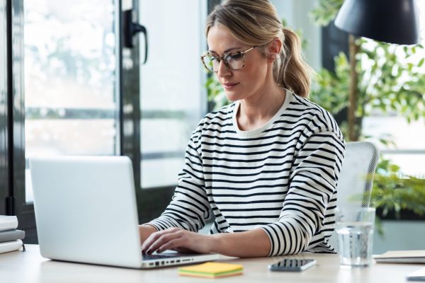 Shot of business woman working while typing with a laptop on a desk in the office at home.