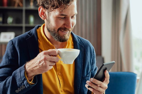 Man Enjoying Coffee While Using Smartphone